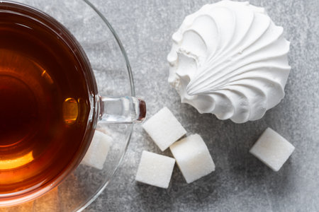 Cup of tea with marshmallow and sugar cubes on grey backgroundの写真素材
