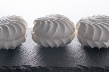 Three white zephyr on a black slate plate isolated on white backgroundの写真素材