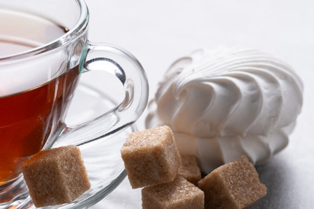 Cup of tea with marshmallow and sugar cubes on light backgroundの写真素材