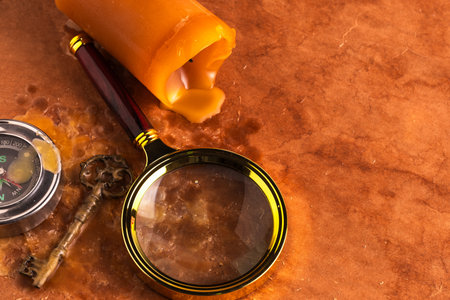 Old compass,  key,  magnifying glass and candle on brown background.の写真素材