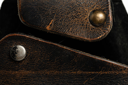 Close up of a black leather case with rivets on white background