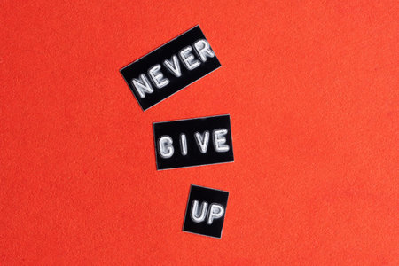 Black label on red background with the words NEVER GIVE UPの写真素材