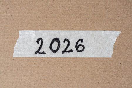New year text on torn paper on brown cardboard box background.