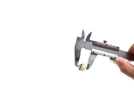 Vernier caliper with dice in hand on white background.の写真素材