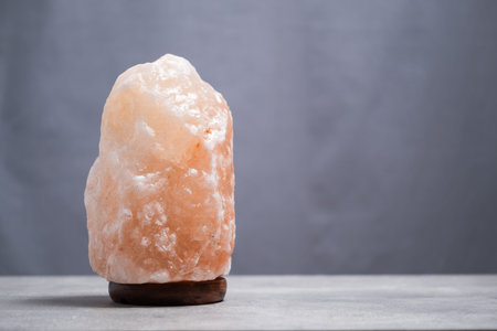 Himalayan salt lamp on wooden stand on gray background.の写真素材
