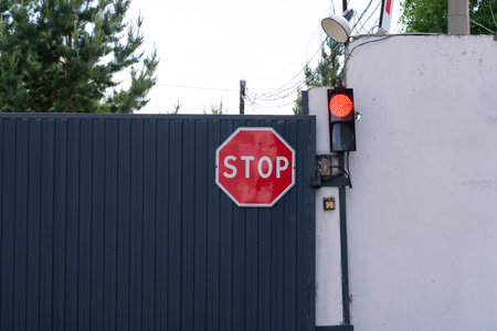 Stop sign on gate. Traffic light on  wall with  red warning sign.