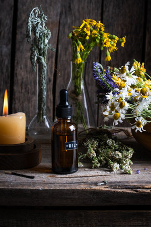 Essential oil in a glass bottle with wildflowers and candlesの写真素材
