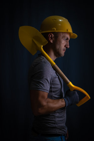 Portrait  construction worker with  shovel on dark background.