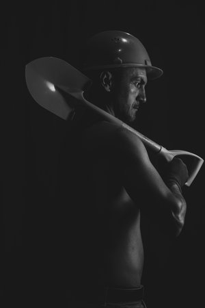 Portrait of a man with a shovel on a black background.