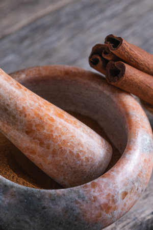 Mortar and pestle with cinnamon sticks on wooden background.の写真素材