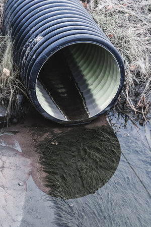 Plastic drainage pipe in a river. Water pollution. Selective focus.の写真素材