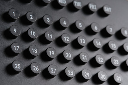 Days   week and numbers on stylish black calendar in close up.