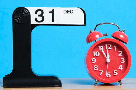 Red alarm clock on blue background and  calendar with  date December 31.の写真素材