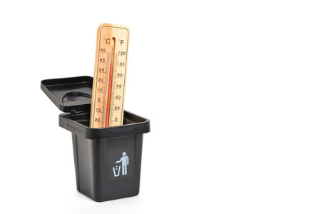 Thermometer in a black trash can isolated on white background.