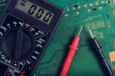 Digital multimeter on the background of the printed circuit board close-up