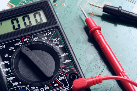 Digital multimeter on circuit board background, closeup of electronic device