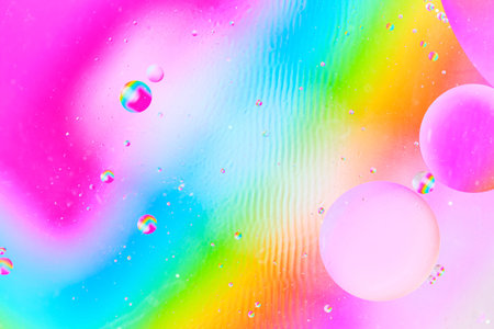 Multicolored abstract macro of oil spheres on rainbow gradient background with liquid ripples