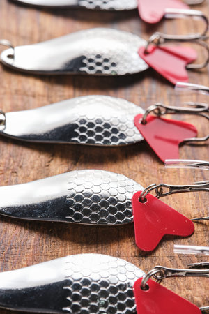 Set of fishing lures with scale pattern and treble hooks on light wooden surface. Top view of...