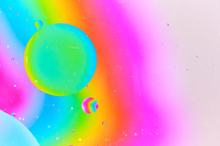 Dynamic macro photography featuring large green blue oil bubble and smaller rainbow colored bubble...