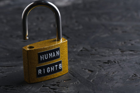 Open golden padlock with Human Rights sign on dark background, conceptual image of freedom and...