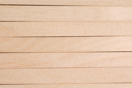 Full frame background closely aligned wooden sticks. Natural light wood grain texture
