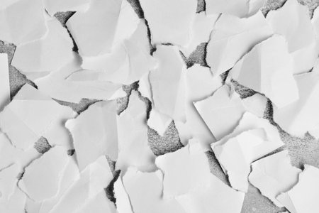 High contrast composition torn white paper pieces layered over dark textured surface
