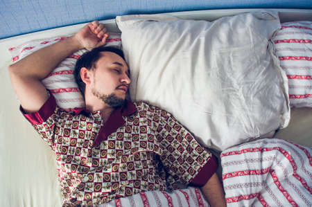 single man sleeping soundly in her bedの写真素材