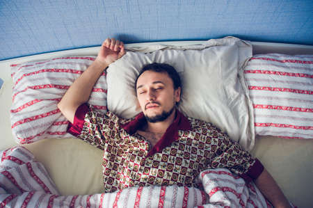 a man in a deep sleep, opened his arms on the pillowの写真素材