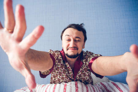 man pulls his hands and smiles at the cameraの写真素材