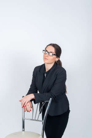 A young girl stands in Studio leaning on the back of a chairの写真素材