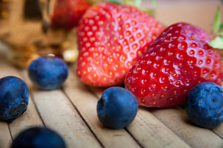 Two strawberries and some grapes a blueberries on wooden backgroundの写真素材