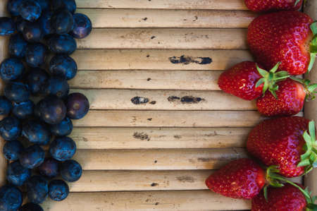 Strawberries and blueberries opposite each other on a wooden backgroundの写真素材