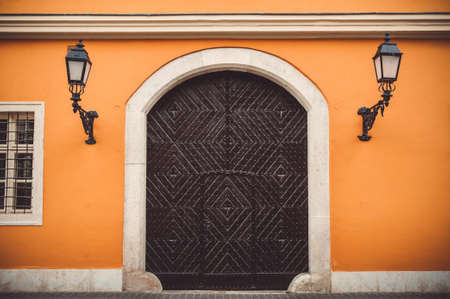 Old wooden door in orange wall with lanterns on the streets of Budapest, Hungary.の写真素材