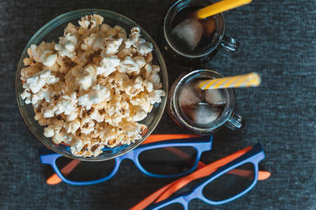 Cola with ice, popcorn in a clear bowl and 3D glassesの写真素材