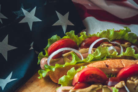 two fresh hot dogs on a wooden Board, glasses with Cola and American flagの写真素材