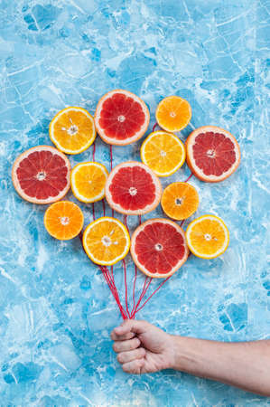 Orange, tangerine and grapefruit in conjunction as balloons, the hand holding the strings.の写真素材