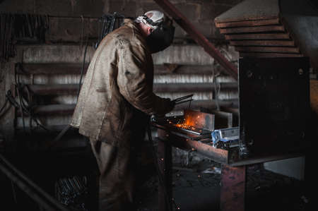 The job of a welder. A large concrete products plant and welding on it.