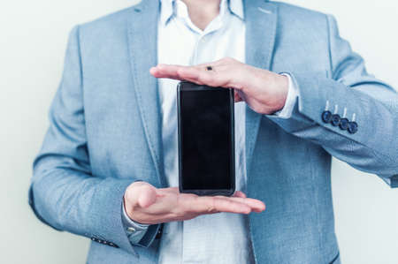 New shiny phone in male hands on a gray backgroundの写真素材