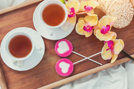 Breakfast in bed in Valentines day. Cup of tea and sweet candies. Love or holiday concept.の写真素材