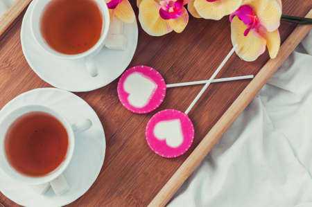 Breakfast in bed in Valentines day. Cup of tea and sweet candies. Love or holiday concept.の写真素材