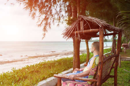 A man sitting in a gazebo and looking at the oceanの写真素材