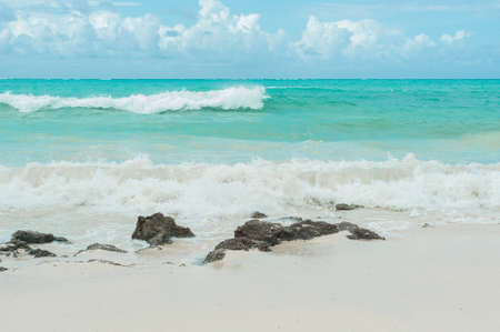 Turquoise waves of the Indian ocean run on the white beach of the island of Zanzibar.