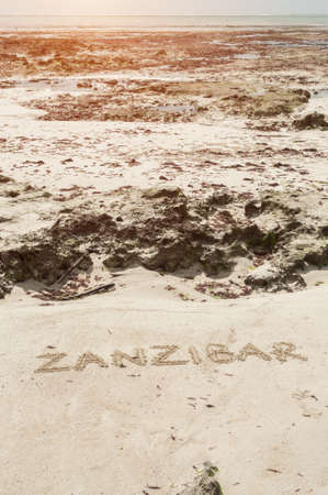 Inscription Zanzibar, Tanzania on the light sand on the beach at low tide.の写真素材