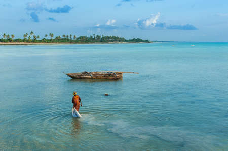Local woman collects algae in the ocean on the island of Zanzibar, Jambiani beach. The life and work of local residents.の写真素材