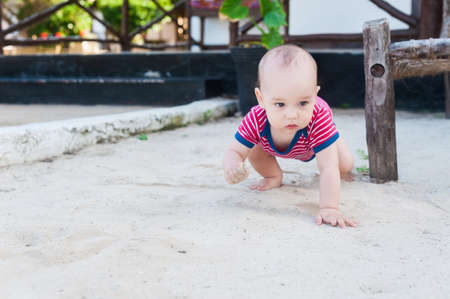 A little boy playing on a white sand. Child with toys for the sandbox. Baby crawling on a sandy beach.の写真素材