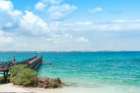 The wooden pier goes into the blue ocean. Tropical landscape with turquoise sea on the island of Zanzibar.の写真素材
