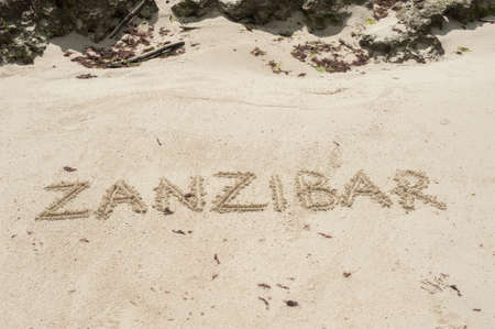 Inscription Zanzibar, Tanzania on the light sand on the beach at low tide.の写真素材