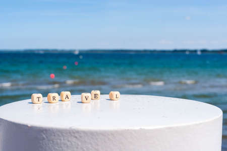 Word Travel on the background of the sea. Letters on wooden cubes on white and sand backgrounds