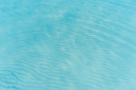 Pure clear turquoise water with sand bottom background