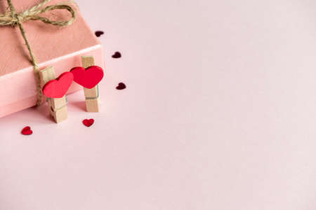 Two hearts on a clothespin on a pink background next to a gift box. Valentine's day background. Concept for packaging, greeting card or design for the holiday.の写真素材